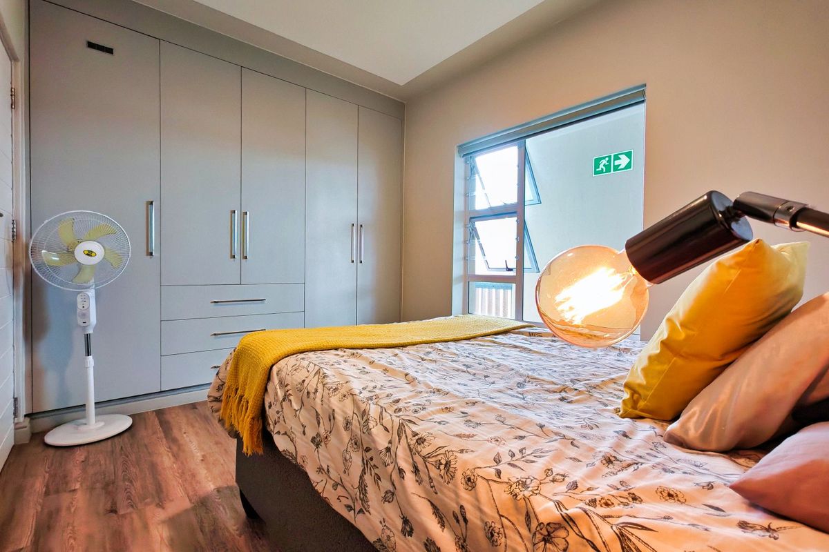 A well-maintained bedroom featuring built-in floor-to-ceiling cabinetry, wood-look flooring, and a window providing natural light.