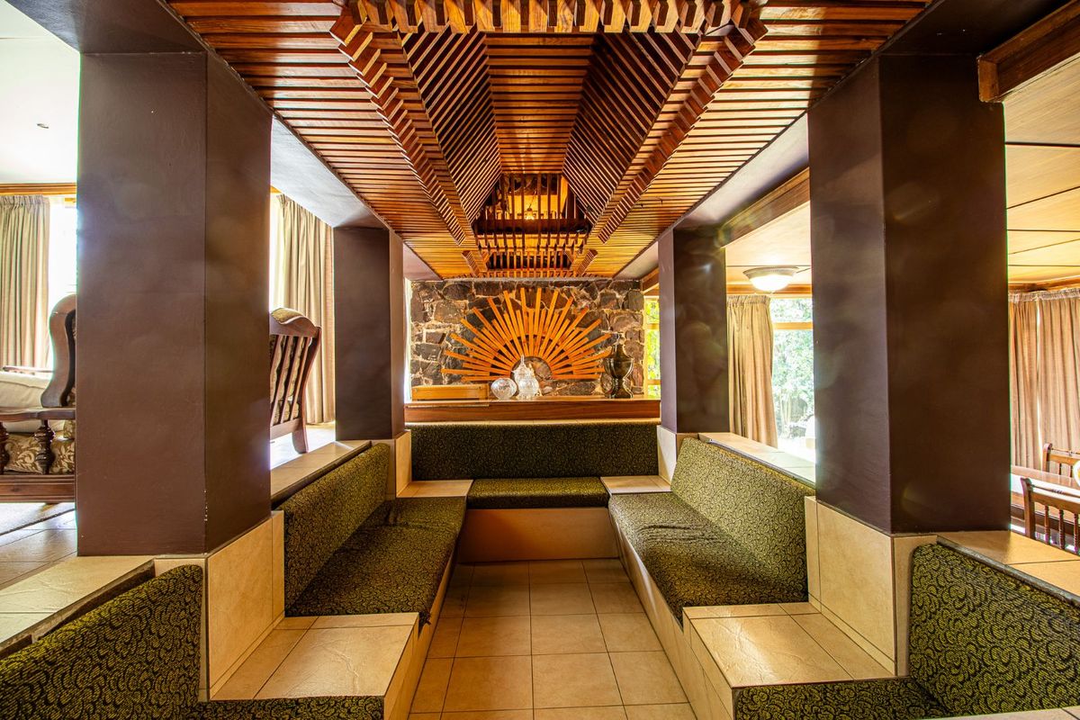 A unique living area featuring custom built-in seating, a stone feature wall, and an intricate timber slat ceiling design.