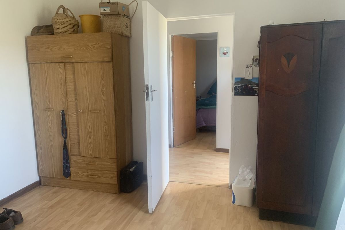 A bedroom featuring light wood-look laminate flooring and a doorway leading to an adjacent room.