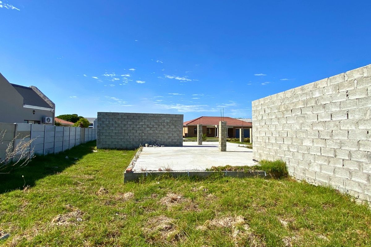 A vacant residential plot featuring an unfinished concrete foundation and partial masonry wall structures, offering a blank canvas for development.
