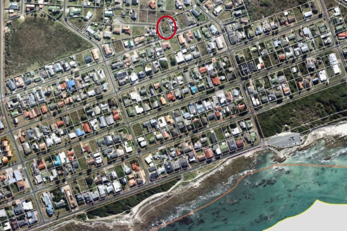 Aerial view of a residential neighborhood highlighting a vacant plot of land within a coastal community.