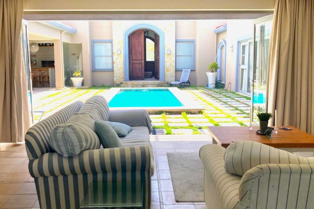A view from the living area looking out through large sliding doors onto a central courtyard featuring a swimming pool and paved garden area.