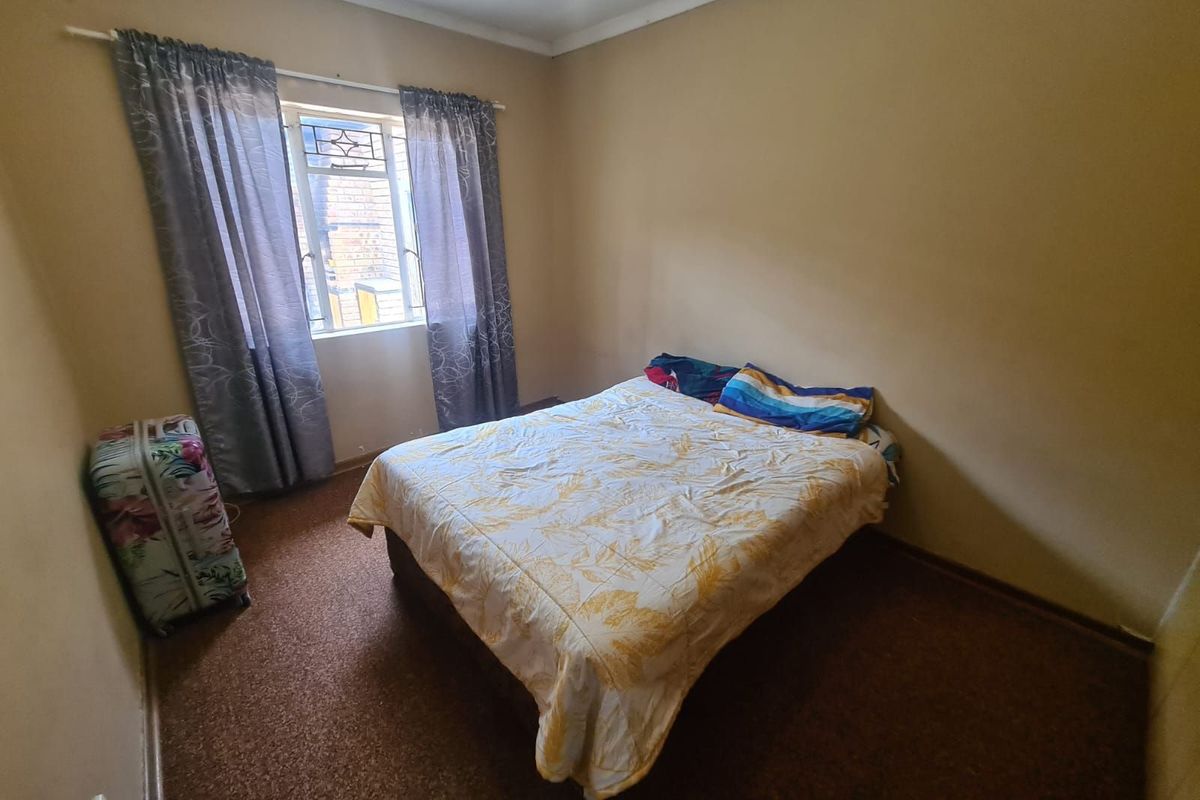 A simple bedroom featuring carpeted flooring and a window with curtain fixtures, offering a functional space ready for updates.
