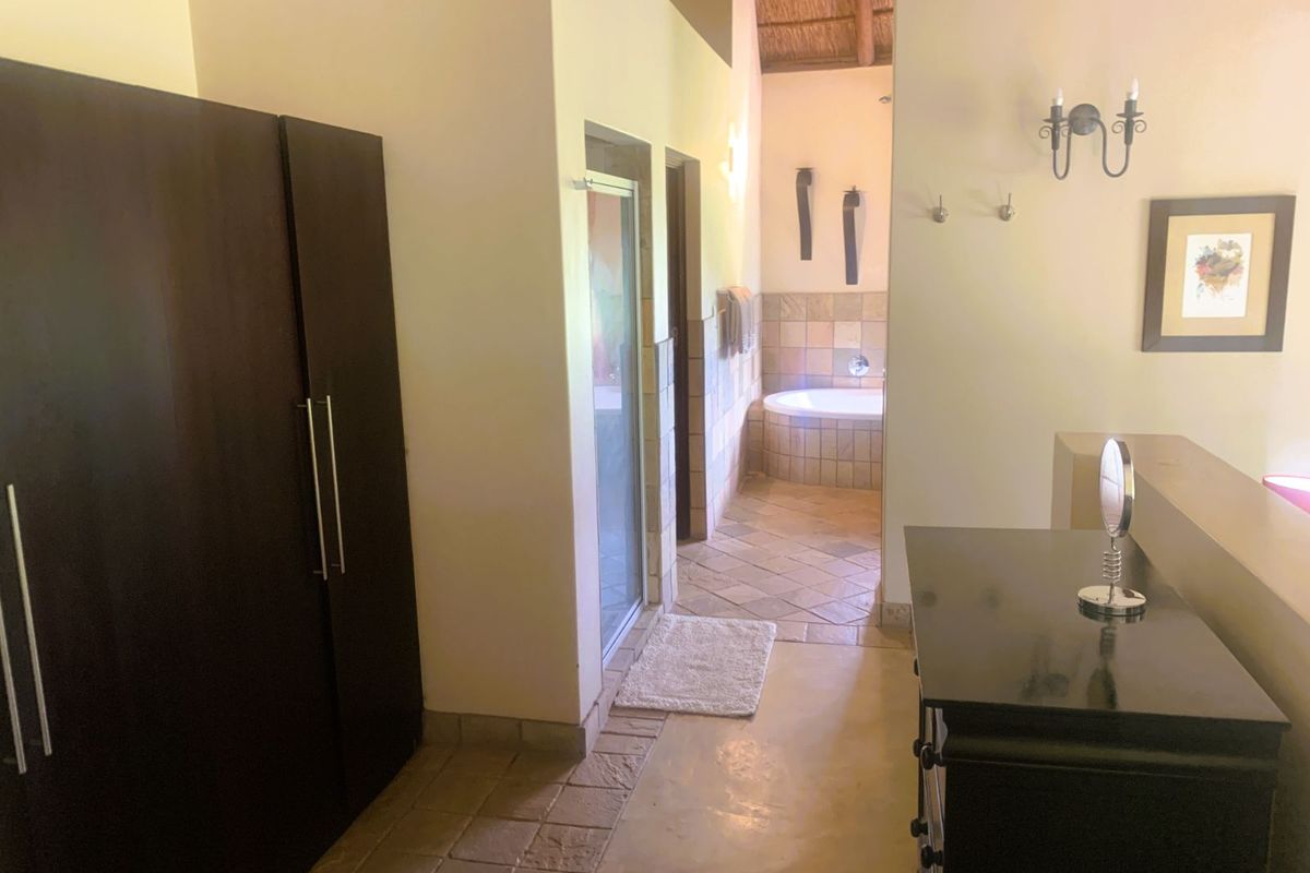 A view of a bathroom area featuring a built-in bathtub, tiled flooring, and a shower enclosure, leading from a dressing or hallway space.