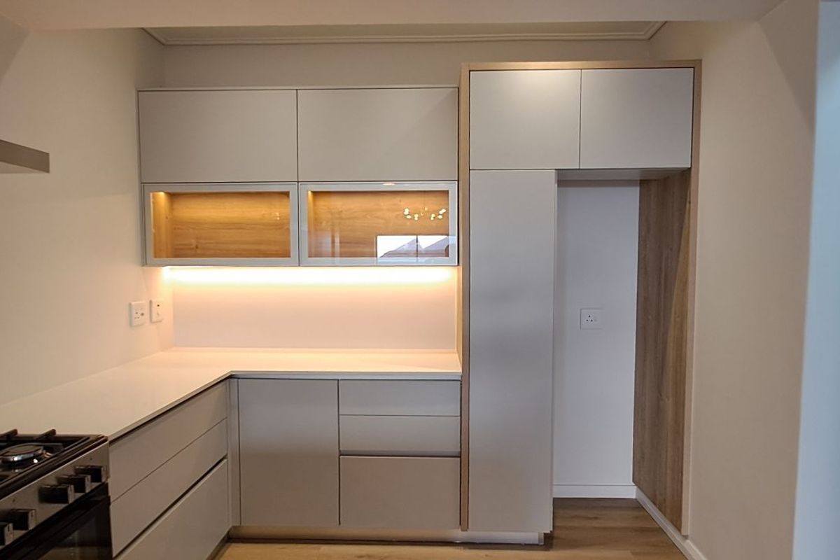 Modern kitchen featuring sleek cabinetry, integrated lighting, a gas stove with extractor fan, and a dedicated space for a refrigerator.