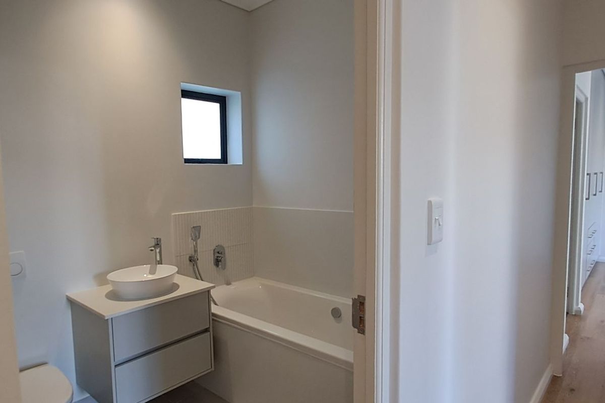 A modern bathroom featuring a white vanity with a vessel sink, a built-in bathtub, and neutral wall finishes.