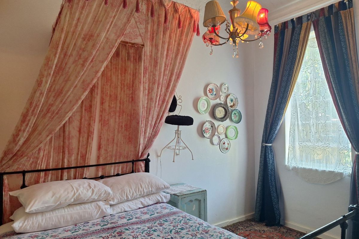 A bedroom featuring a classic metal bed frame, a decorative chandelier, and a window with natural light.