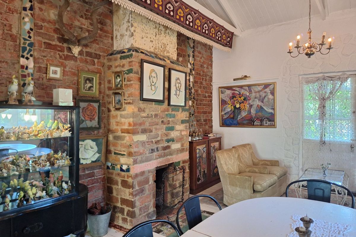 A character-filled living area featuring a prominent exposed brick fireplace, vaulted ceilings, and unique architectural detailing.