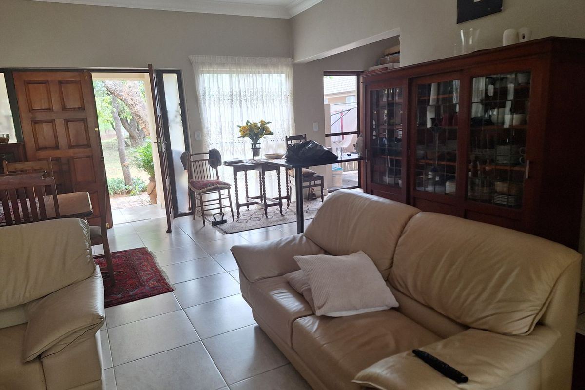 A living room area featuring tiled flooring, crown molding, and direct access to an outdoor patio through glass doors.
