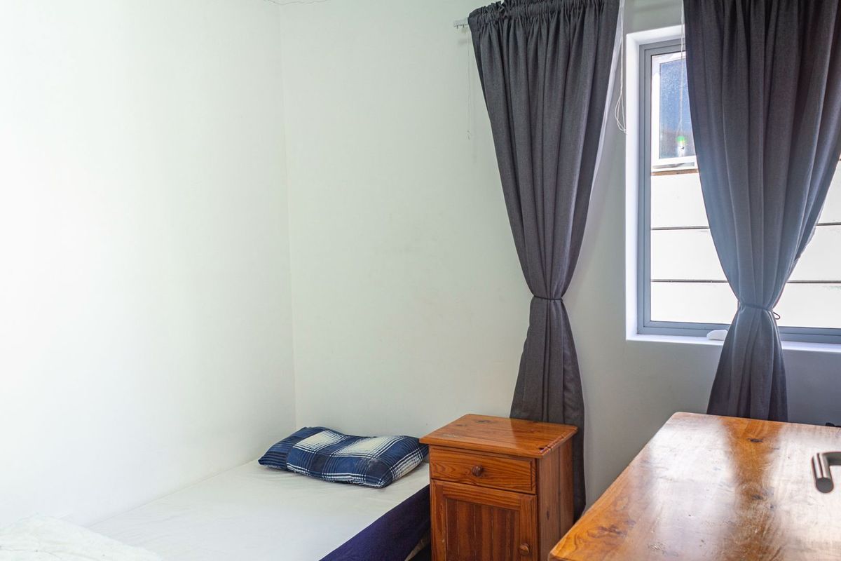 A simple bedroom featuring a window with curtains, providing natural light and a neutral backdrop for personalization.