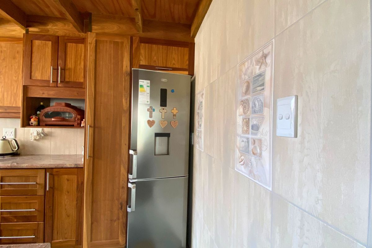 A kitchen area featuring wooden cabinetry, tiled walls, and a built-in cupboard space for a refrigerator.