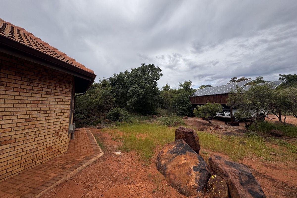 Exterior view of the property featuring a brick facade, paved walkway, and a separate structure equipped with solar panels.