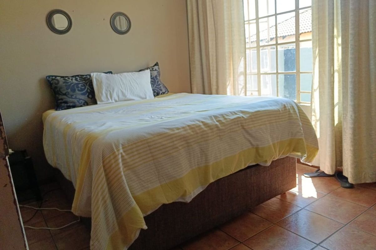A bedroom featuring tiled flooring and a large window with natural light, providing a functional and comfortable living space.