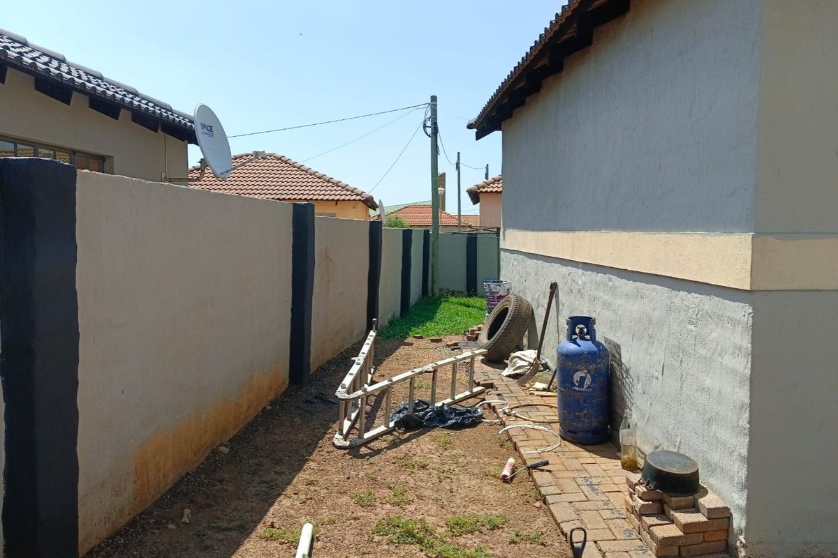 A narrow side exterior area featuring a boundary wall and paved walkway along the side of the house.