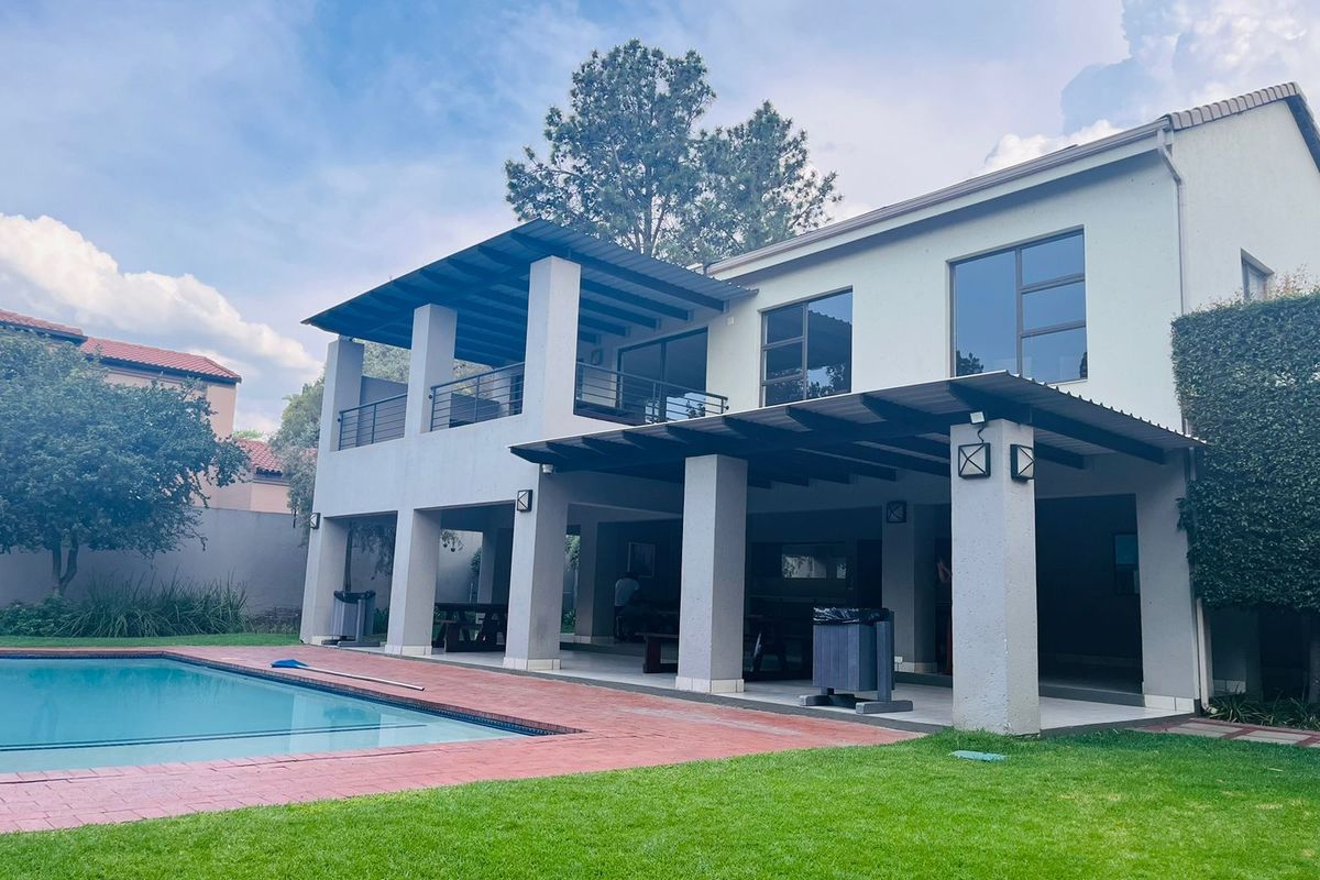 Rear view of the apartment featuring a covered patio, swimming pool, and landscaped garden area.