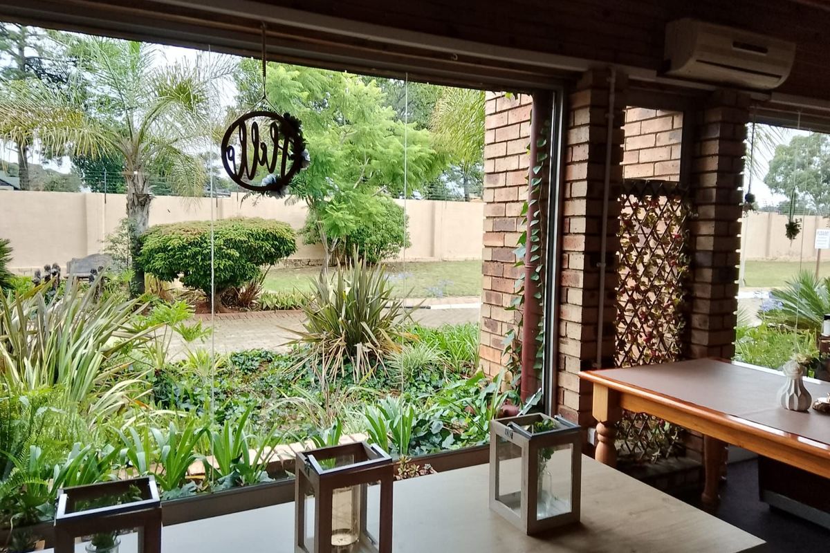 A bright indoor space featuring large glass sliding doors that provide a seamless view of the landscaped garden and brick boundary wall.