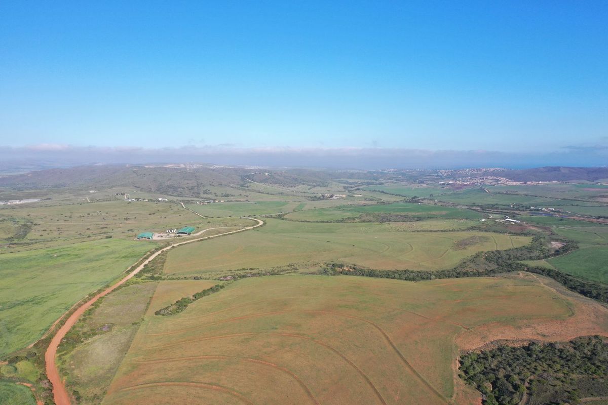 An expansive aerial view of the farm property, showcasing vast open fields, rolling landscape, and access roads under a clear blue sky.