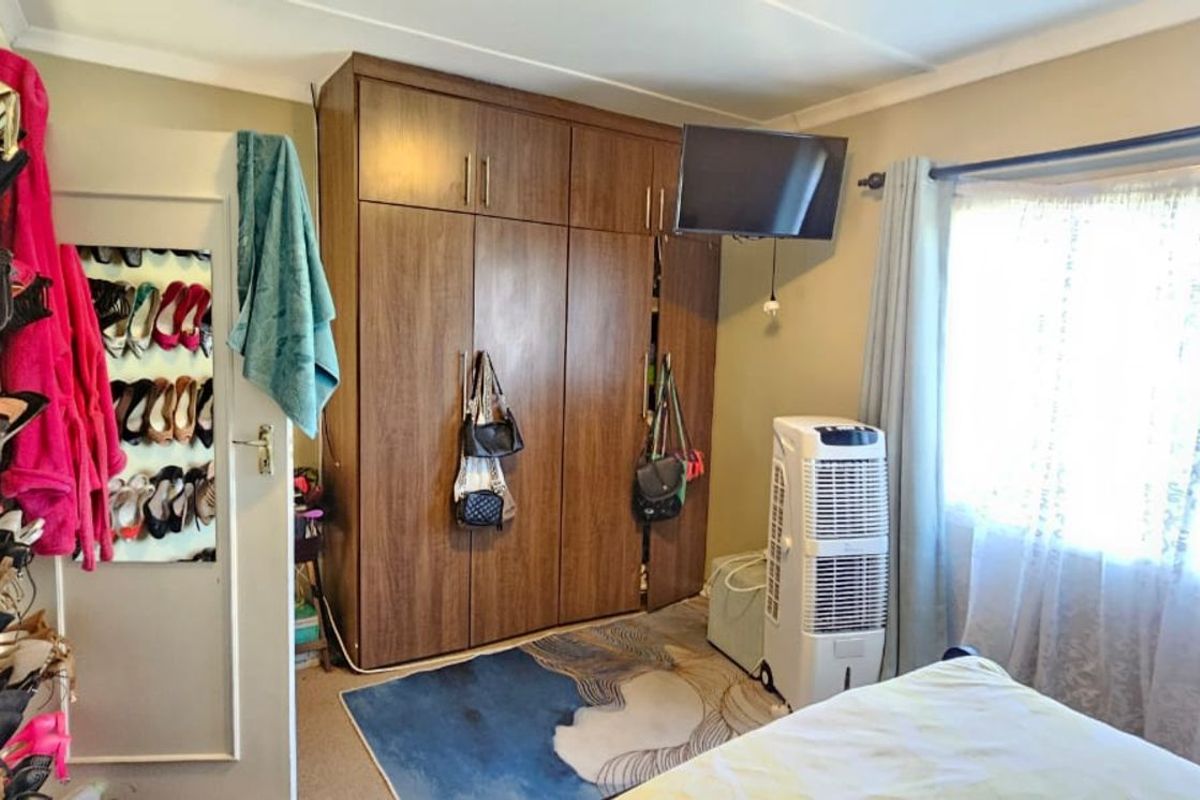 A bedroom featuring built-in wooden cabinetry and a window with curtains, providing functional storage and natural light.