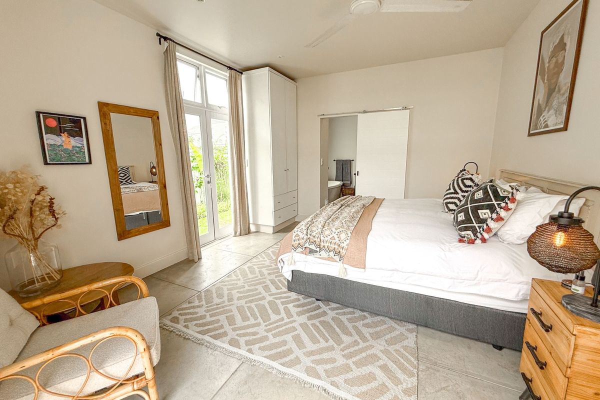 Spacious bedroom featuring tiled flooring, built-in wardrobe, ceiling fan, and direct access to the garden through glass panel doors.