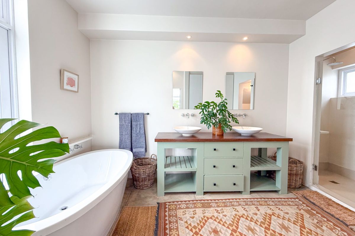 A bright, modern bathroom featuring a freestanding soaking tub, a custom dual-sink vanity with a wooden countertop, and a separate walk-in shower.
