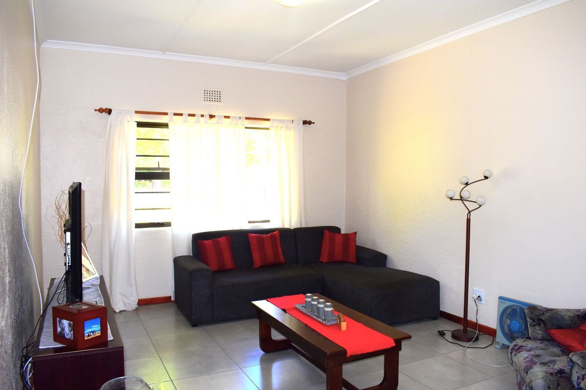A living room featuring tiled flooring, textured walls, and a window with curtain rod.