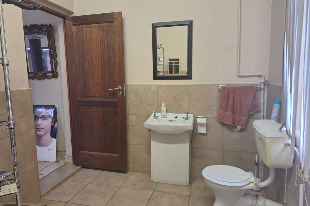 A functional bathroom featuring a pedestal sink, a standard toilet, and tiled walls and flooring.