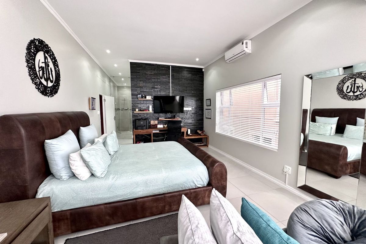 Spacious bedroom featuring a dark stone feature wall, tiled flooring, integrated air conditioning unit, and an en-suite bathroom access.