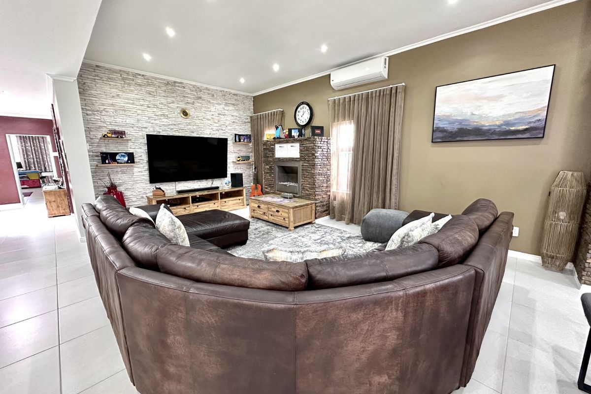 Spacious living room featuring a stone-clad feature wall, built-in fireplace, recessed downlighting, and split-system air conditioning unit.