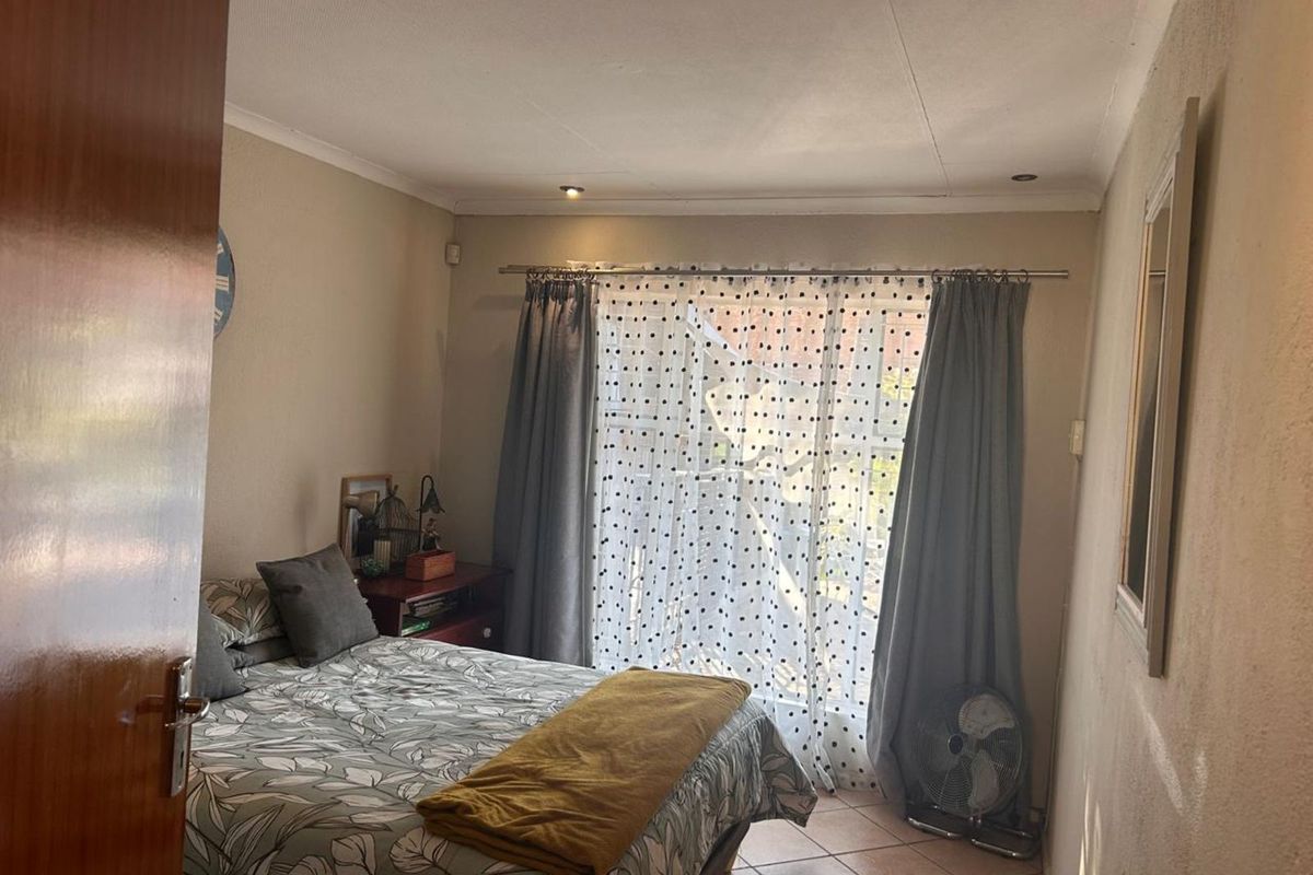 A standard bedroom featuring tiled flooring, recessed ceiling lighting, and a large window with curtain tracks.