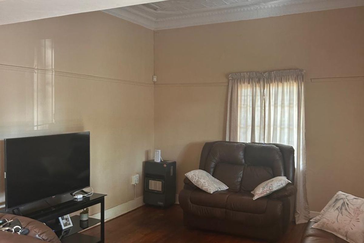 A living room featuring original timber flooring, decorative ceiling cornices, and a built-in gas heater connection.
