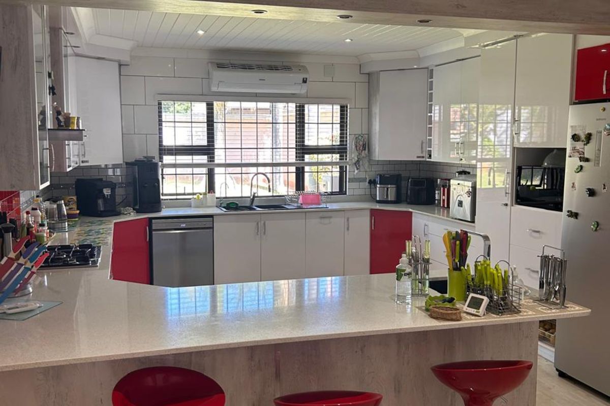 A functional kitchen featuring a breakfast bar, built-in cabinetry, integrated sink, and tiled backsplash, offering a practical layout for daily cooking and dining.