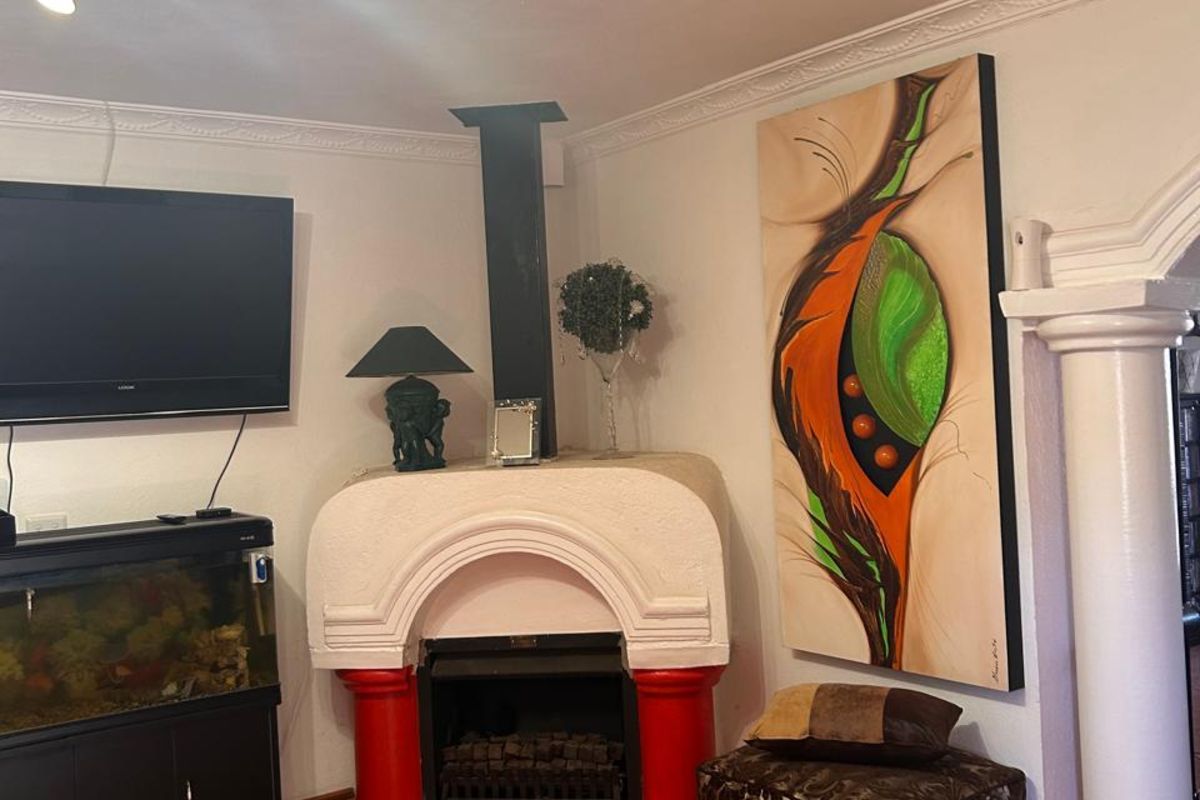 Living room featuring a corner fireplace with a decorative mantle, terracotta floor tiles, ornate ceiling rose, and classic architectural column detail.