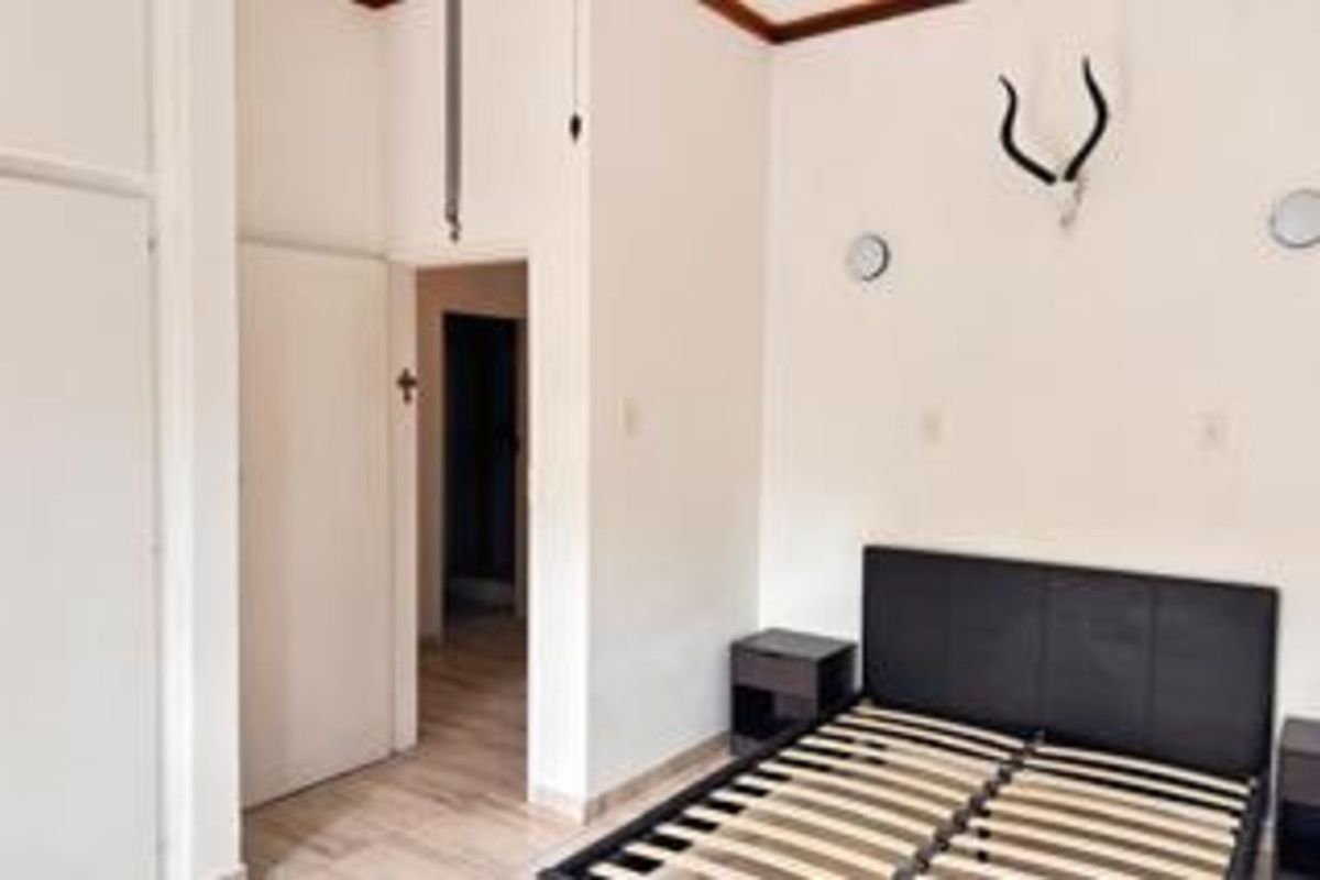 A bedroom featuring neutral walls, tiled flooring, and built-in cupboard space, providing a functional and simple living area.