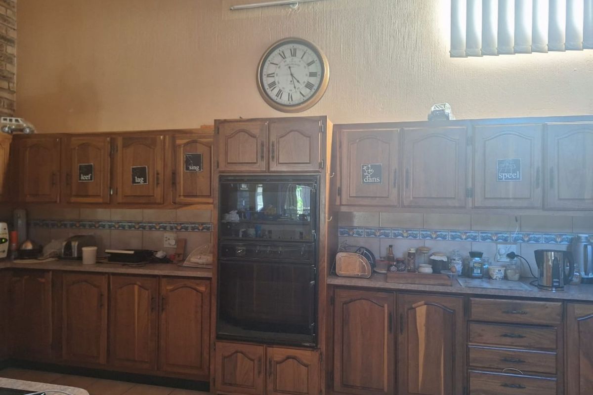 A traditional kitchen featuring wood-finish cabinetry, built-in double oven, and decorative tiled backsplash, offering a functional layout with ample storage space.