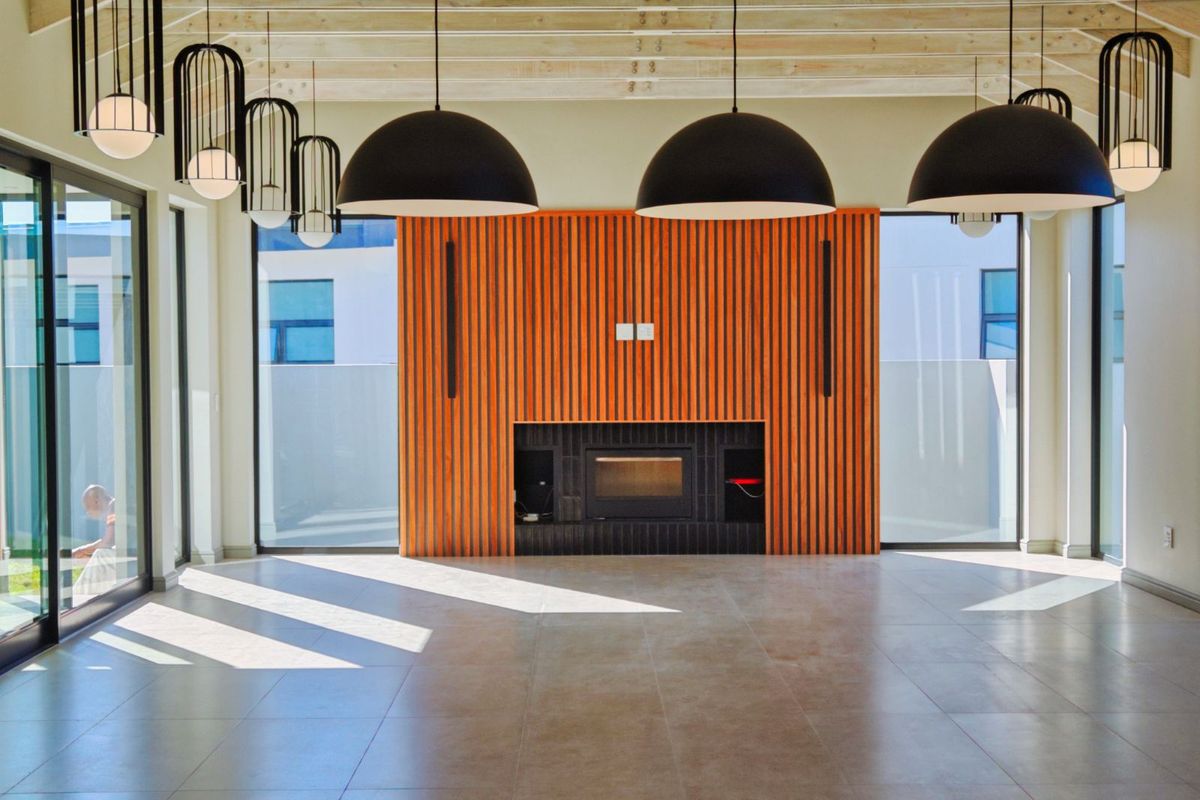 Spacious living area featuring a modern fireplace with timber slat feature wall, large glass sliding doors, and contemporary pendant lighting.
