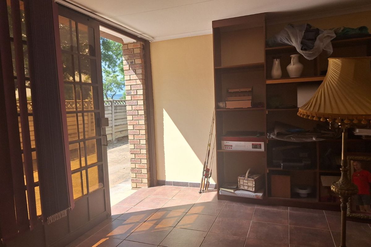 A functional interior space featuring tiled flooring, built-in wooden shelving, and a glass-paneled door providing direct access to the exterior.