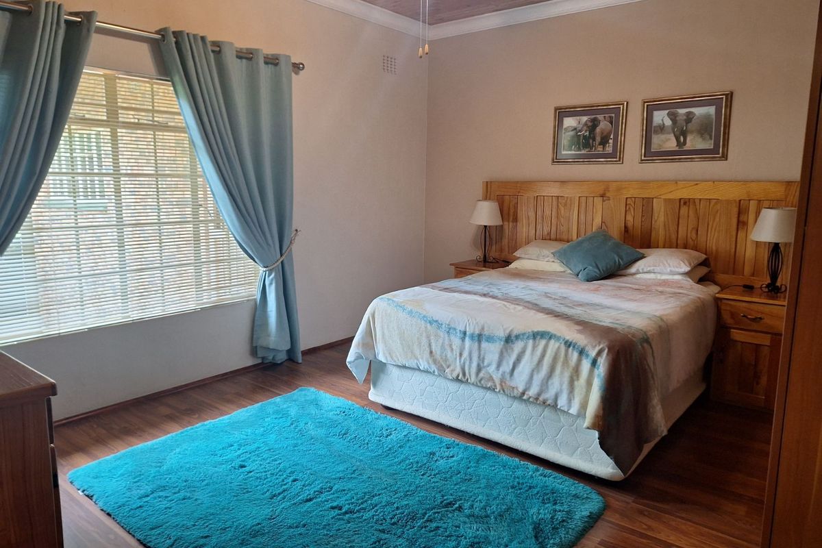 A well-maintained bedroom featuring wood-look flooring, a timber-paneled ceiling, and a built-in wooden headboard.