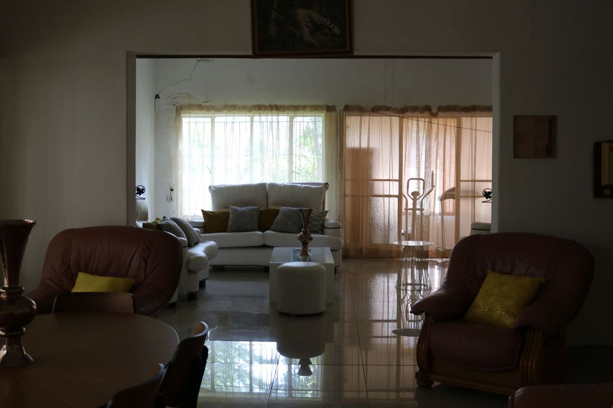 Spacious living area featuring large windows, tiled flooring, and an open-plan layout connecting to an adjacent room.