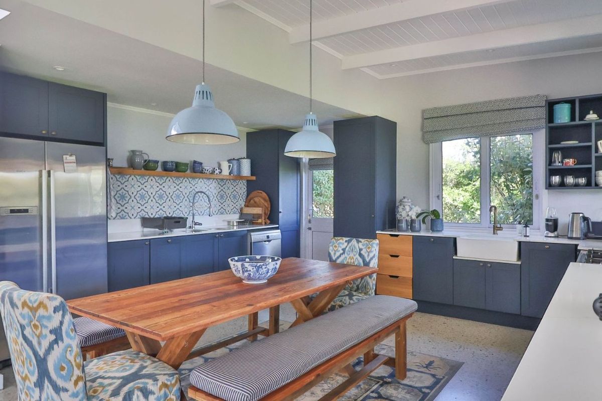 A well-appointed kitchen featuring blue cabinetry, a farmhouse sink, patterned tile backsplash, and integrated shelving, creating a functional and stylish culinary space.