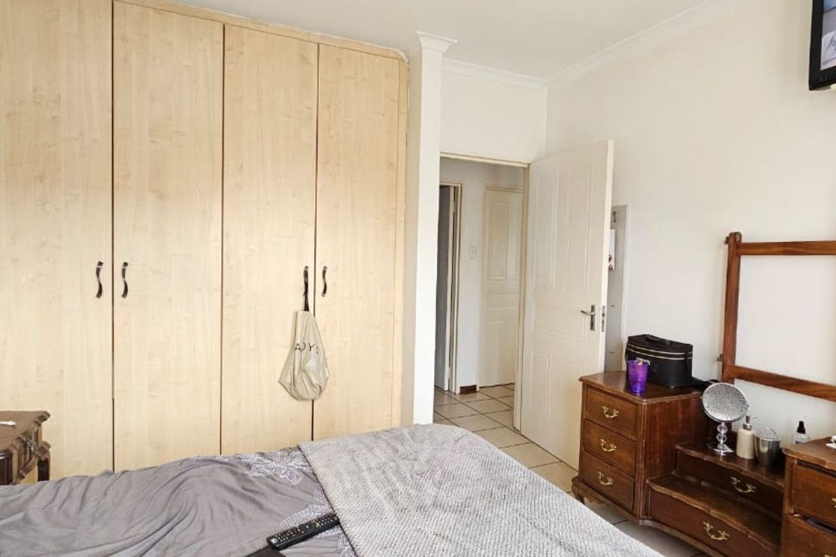 A bedroom featuring built-in light wood cabinetry and tiled flooring, providing functional storage space and access to the hallway.