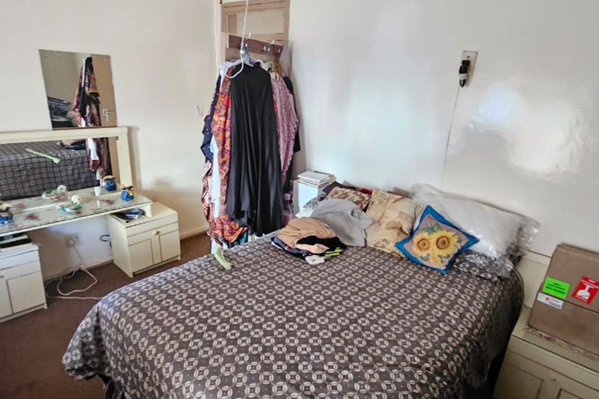 A bedroom featuring carpeted flooring, a built-in vanity unit with mirror, and standard electrical fixtures.