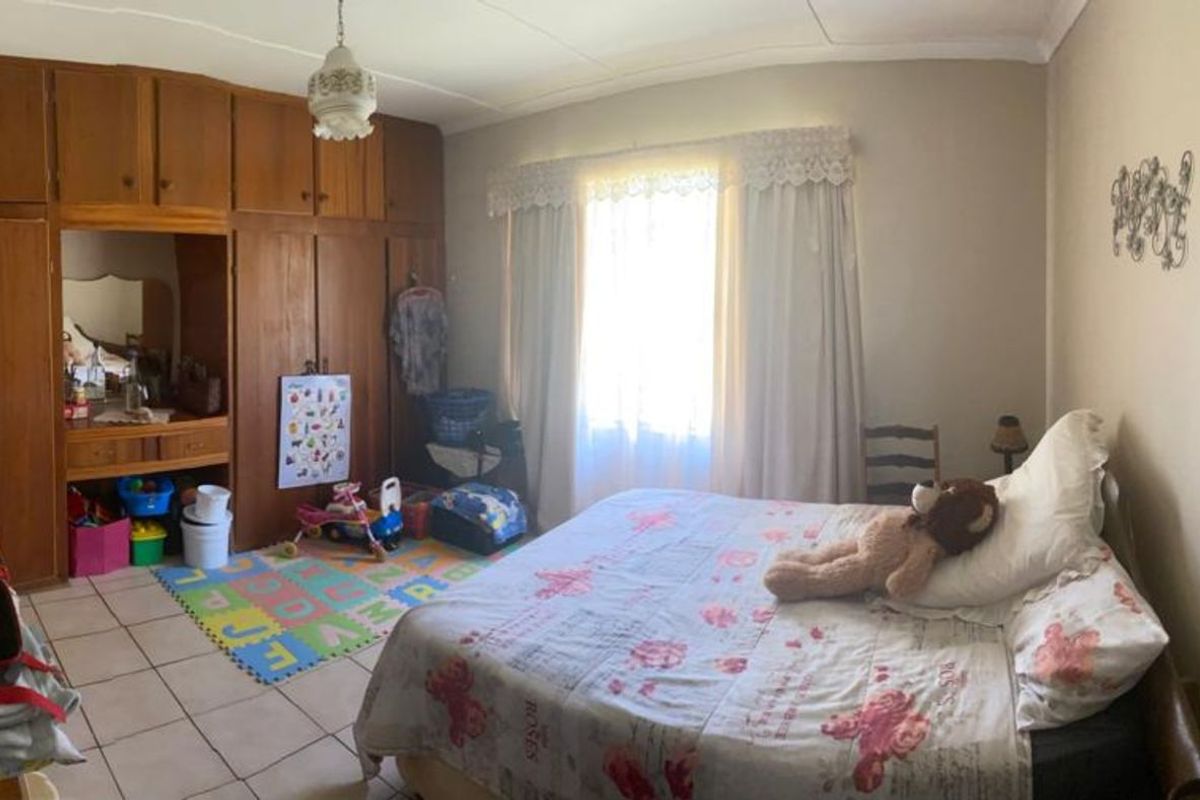 A bedroom featuring built-in wooden cupboards and tiled flooring, offering functional storage space and natural light.