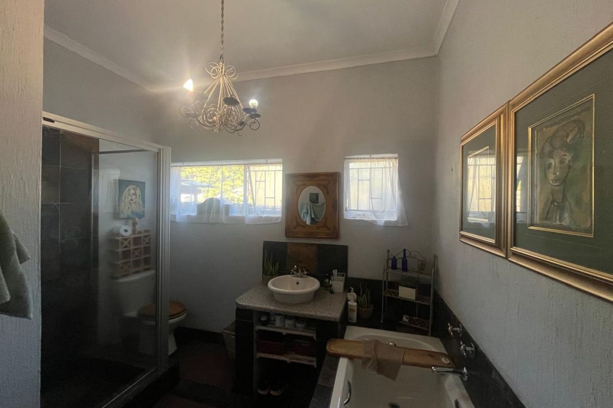 A functional bathroom featuring a glass-enclosed shower, a built-in vanity with a vessel sink, and a separate bathtub under a decorative chandelier.