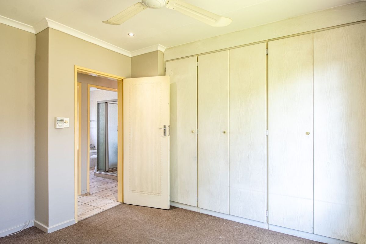 Bedroom featuring built-in wardrobes, neutral wall finishes, and an adjoining en-suite bathroom with a shower.