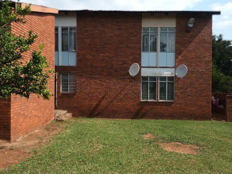 A view of the rear brick facade of the house, featuring multiple windows and a private garden area.