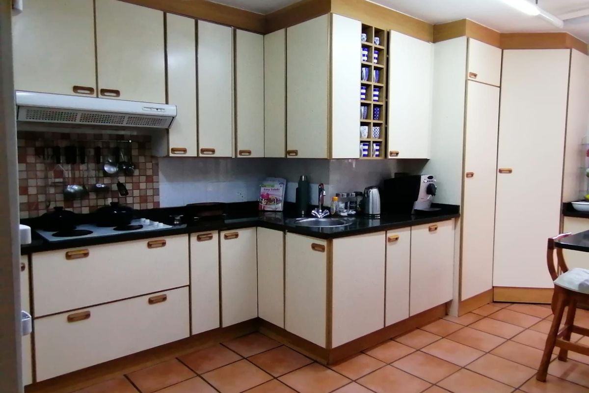 A functional kitchen featuring laminate cabinetry, dark countertops, a built-in extractor fan, and tiled flooring.
