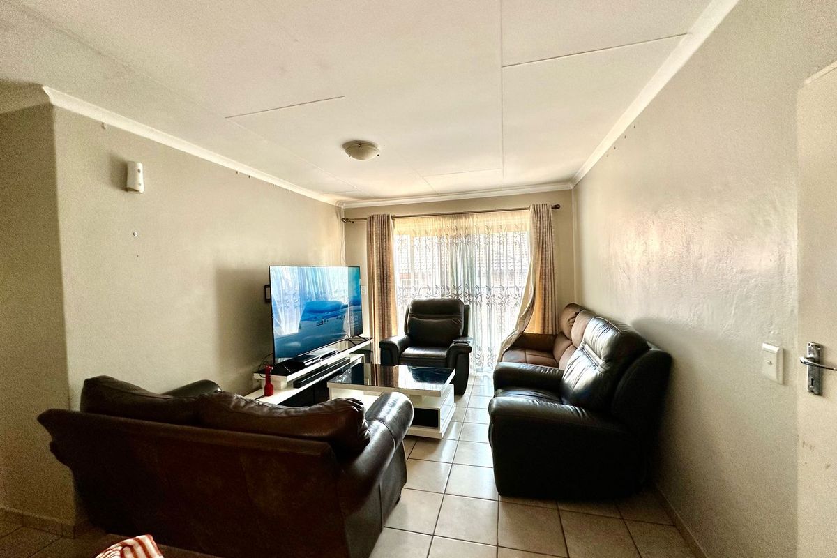 A functional living room featuring tiled flooring, neutral wall finishes, and a sliding glass door providing natural light and access to the exterior.