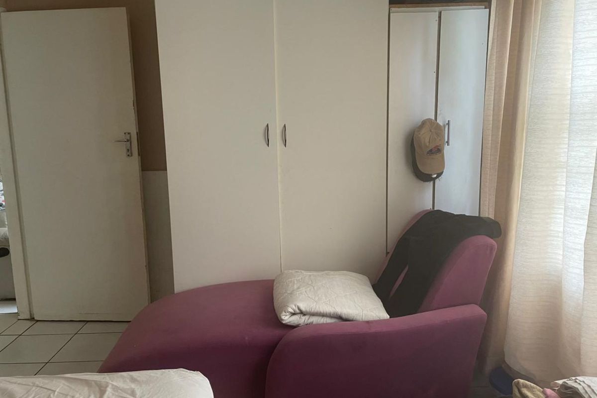 A bedroom featuring built-in white cabinetry and tiled flooring, providing functional storage space within the apartment.