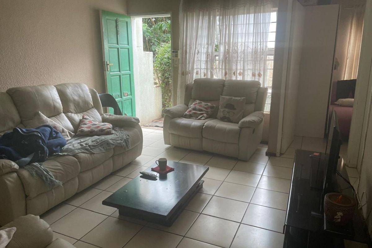 A living room featuring ceramic floor tiles and direct access to an outdoor area through a green door.