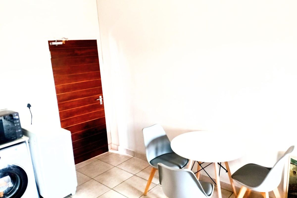 A functional living area featuring tiled flooring and a solid timber door, providing a clean and neutral space.